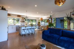 a living room and kitchen with a blue couch at Te Makiri House, Onetangi - Be My Guest Waiheke in Waiheke Island