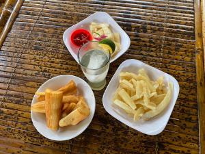 three plates of food with french fries and a glass of water at Gina's Reading Homestay in Pulau Lebur