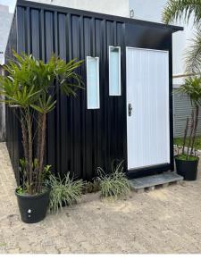 un cobertizo blanco y negro con una puerta blanca en Capão da Canoa - Quarto Aconchegante na Praia!, en Capão da Canoa