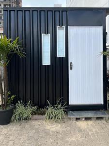 un edificio blanco y negro con una puerta blanca en Capão da Canoa - Quarto Aconchegante na Praia!, en Capão da Canoa