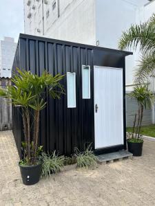 un cobertizo blanco y negro con una puerta blanca en Capão da Canoa - Quarto Aconchegante na Praia!, en Capão da Canoa
