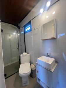 Un baño con inodoro, lavabo y ducha. en Capão da Canoa - Quarto Aconchegante na Praia!, en Capão da Canoa