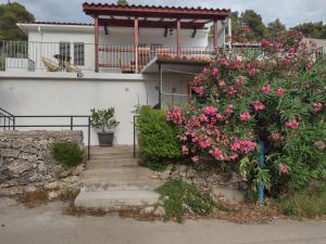 une maison blanche avec des fleurs roses dans les escaliers dans l'établissement Two Bedroom Apartment With Terrace And Sea View, à Otočić Ošjak