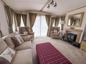 a living room with a couch and a fireplace at 6 Berth Caravan With Decking At Caister Haven Holiday Park Ref 30032P in Great Yarmouth