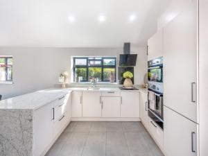 Una cocina blanca con gabinetes blancos y un fregadero. en Lower Peastocking, en Meriden