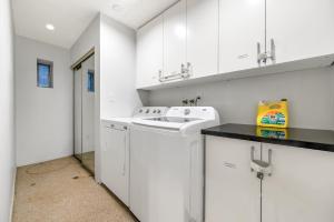 バンクーバーにあるSpacious 3BR with Full Kitchen a n dFast Wi-Fiのキッチン(白いキャビネット、洗濯機、乾燥機付)