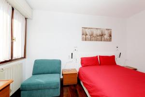 a bedroom with a red bed and a blue chair at Luxury Panoramic Apt w Garage Happy Home Bergamo 2 in Bergamo