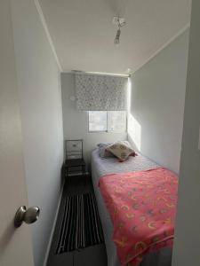 a small bedroom with a bed with a pink blanket at Departamento equipado 203 Ovalle in Ovalle