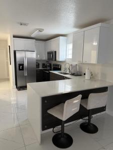 ハイアリーアにあるVilla Miami Lakes 2のキッチン(白いキャビネット付)、カウンター(椅子2脚付)