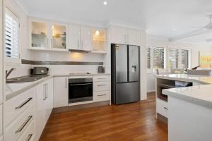 Una cocina con gabinetes blancos y un refrigerador de acero inoxidable. en Wave Whisperer, en Kingscliff