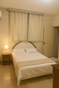 a bedroom with a large white bed with a window at Hotel Lídia in Fortaleza