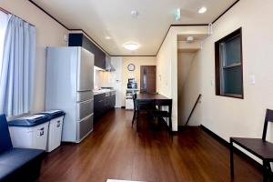 eine Küche mit einem Kühlschrank und einem Tisch im Zimmer in der Unterkunft アツギハウス Max 12 ppl Free parking 3story detached house in Osaka