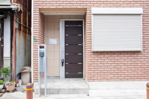 eine Tür zu einem Backsteingebäude mit einem Fenster in der Unterkunft アツギハウス Max 12 ppl Free parking 3story detached house in Osaka