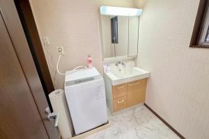 ein kleines Bad mit einem Waschbecken und einer Waschmaschine in der Unterkunft アツギハウス Max 12 ppl Free parking 3story detached house in Osaka + 73 Fotos