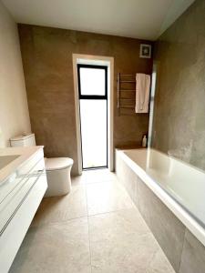 a bathroom with a tub and a toilet and a sink at Hot Tub and Views in Castle Hill +16 photos