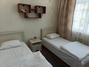 two twin beds in a room with a window at Worldly Home in Mekhrably