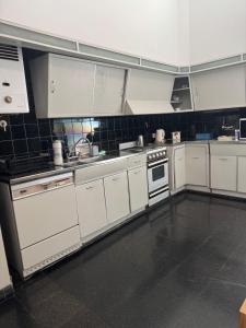 una cocina con electrodomésticos blancos y azulejos negros en La Casona, en Alta Gracia