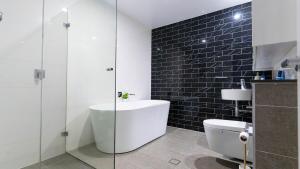 une salle de bain avec toilettes et douche en verre dans l'établissement Luxe Sydney Olympic Park Stay - 2BR for 4 Guest, à Sydney 6 autres photos