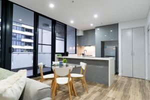 une cuisine et un salon avec une table et des chaises dans l'établissement Luxe Sydney Olympic Park Stay - 2BR for 4 Guest, à Sydney