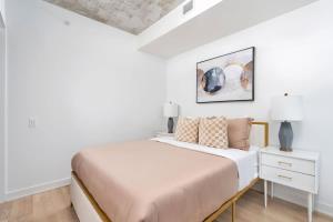 a white bedroom with a bed and a nightstand at Urban Oasis Condo with Cafe & Bar at Your Doorstep in Toronto