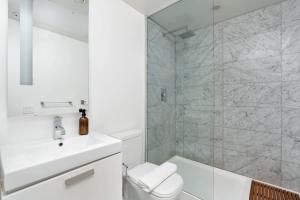 a white bathroom with a toilet and a sink at Urban Oasis Condo with Cafe & Bar at Your Doorstep in Toronto