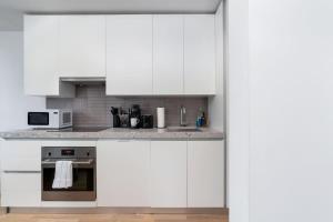 a white kitchen with a stove and a microwave at Urban Oasis Condo with Cafe & Bar at Your Doorstep in Toronto