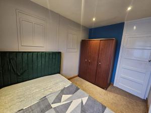 a bedroom with a green bed and a wooden cabinet at Home at Richmond - Conifer Crescent in Nottingham