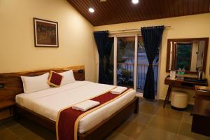 Un dormitorio con una cama y un escritorio y una ventana. en Aldea Retreat Resort, en Kūvattūr 40 fotos más