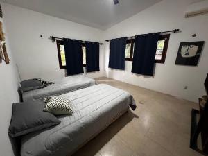 two beds in a room with blue curtains at Casa Manilkara Calakmul in Xpujil
