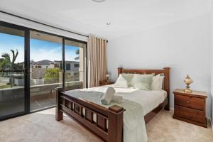 ゴールドコーストにあるSerene 5BR Waterfront Escape - Prestigeのベッドと大きな窓のある寝室 +15枚の写真