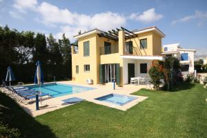 a villa with a swimming pool in front of a house at Kotsias Corallia Villas in Coral Bay