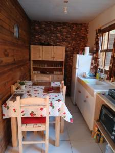 a kitchen with a table with chairs and a refrigerator at Cabaña Faro di luce in Santa Vitória do Palmar