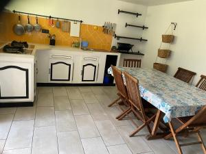 Una cocina con mesa y sillas y una cocina con azulejos naranjas. en Charmante villa située dans l’Est de l’île., en Sainte-Anne 5 fotos más