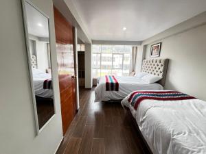 a bedroom with two beds and a mirror at Hotel Inka House Chinchero in Chinchero