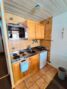 eine kleine Küche mit Holzschränken und einer Spüle in der Unterkunft Serac Lodge in Val Thorens by Alpstays in Val Thorens