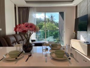 a dining room table with a vase with flowers on it at Bright 2BR Condo near Central Phuket FREE Pool Gym Parking in Ban Ket Ho +32 photos
