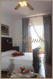 een slaapkamer met een bed, een plafondventilator en een raam bij Alchimia tra suoni e colori in Marina di Mancaversa