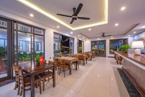 a restaurant with tables and chairs and a ceiling fan at CocoPalm Hoi An River Beach in Hoi An