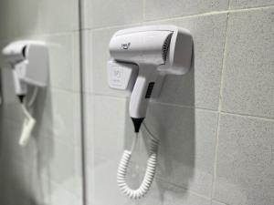 a white hair dryer hanging on a wall at Smile Hotel Titiwangsa Pekeliling Sentul in Kuala Lumpur