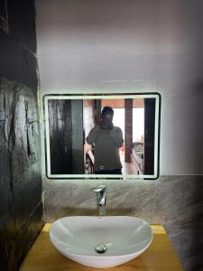 a person taking a picture of a sink in a mirror at Păng Nhù homestay- Venuestay in Bắc Yên