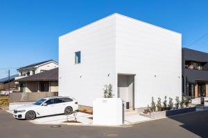 a white car parked in front of a white building at The Rabbit 兎a newly built vacation home in Inzai