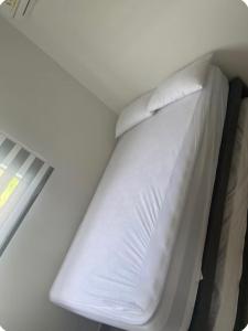 a bed with white sheets and pillows next to a window at Aviva Sierra Santa Marta Comodo y lindo apartamento para tus vacaciones in Santa Marta