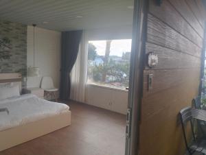 a bedroom with a bed and a large window at Đối diện cafe CATINAT villa Kagen in Da Lat