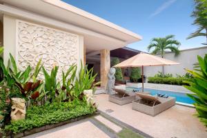 an outdoor patio with a pool and an umbrella at Villa J Deluxe in Canggu