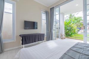 Un dormitorio con una cama y un televisor en la pared. en The Beautiful villa, Casa Sara, en Canggu