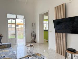Una sala de estar con un sofá y un televisor de pantalla plana. en Sopraia Nature, en Les Abymes