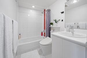 Un baño blanco con inodoro y lavabo. en Modern 2BR Apartment in Gastown Steps from Downtown, en Vancouver