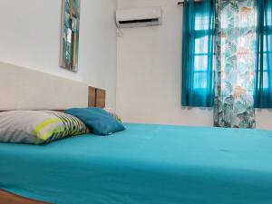 1 dormitorio con cama azul y cortinas azules en Sopraia Nature, en Les Abymes