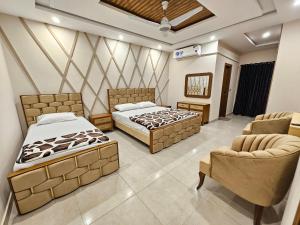 two beds in a room with two chairs and a couch at Noor Residence Cozy Homes G15 in Islamabad
