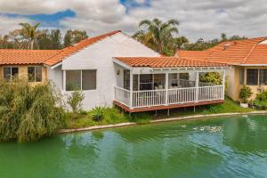 a white house with an orange roof next to a river at The Whitehouse - South Yunderup in South Yunderup